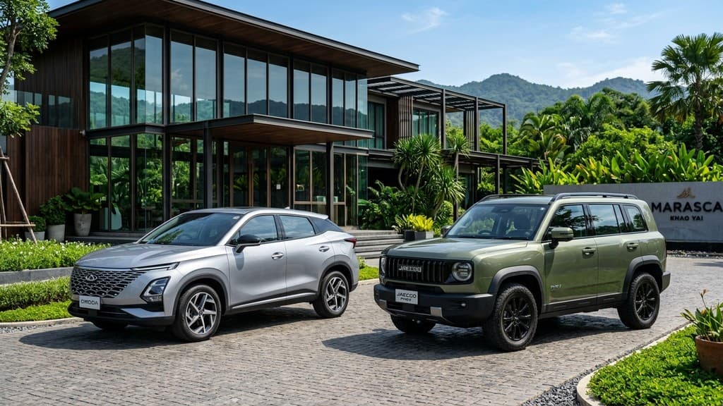 Chery Omoda C9 สีเงิน จอดคู่กับ Jaecoo 7 PHEV สีเขียวมะกอก ด้านหน้ารีสอร์ตหรูสไตล์กระจกโมเดิร์นในเขาใหญ่ ประเทศไทย